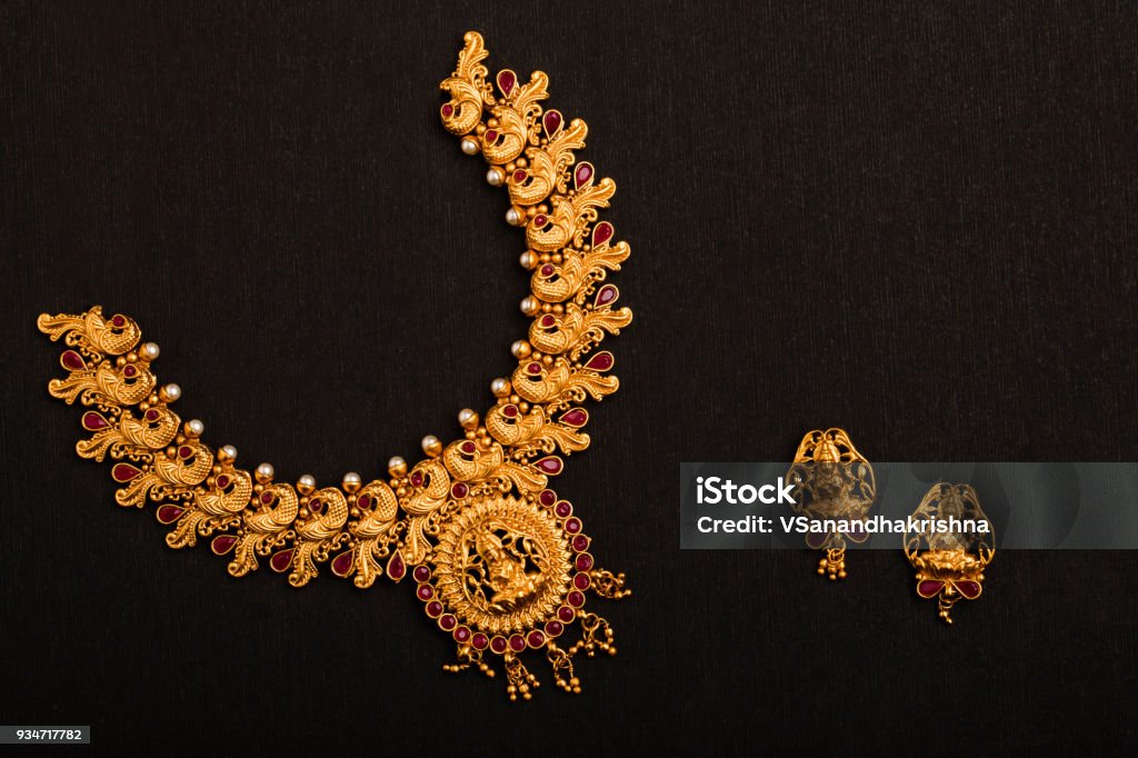 Traditional Indian Gold Necklace with Earrings on black background.